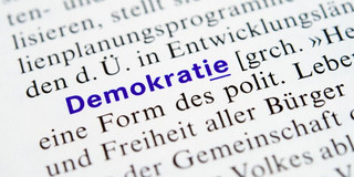 Buchseite mit Text; das Wort "Demokratie" ist blau hervorgehoben.